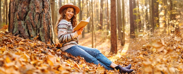 Chica leyendo en el bosque sentada