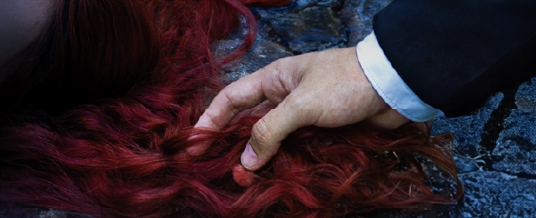 Mano de hombre sujetando cabello pelirrojo de mujer