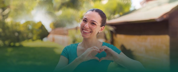Chica sonriendo y haciendo un forma de corazón con sus manos