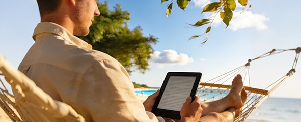 Chico leyendo en un eReader en la playa